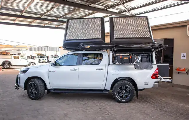 White Toyota Hilux with roof tent parked on desert sand